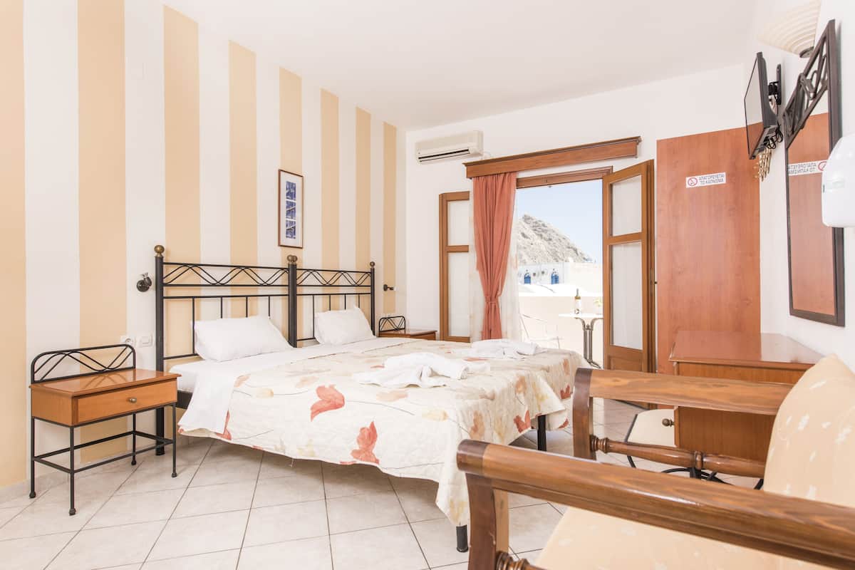 A bedroom with a bed, bedside table, and a view of the outside.