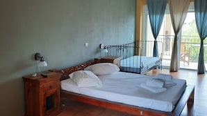 A bedroom with a wooden bed, a nightstand, a lamp, and a view of the outdoors through a balcony. - O Xenonas ton Mylon (Argos-Mykines)
