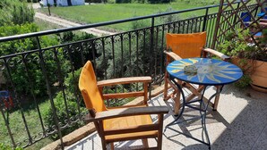 A balcony with a wooden chair and a small round table, surrounded by a metal railing. - O Xenonas ton Mylon (Argos-Mykines)