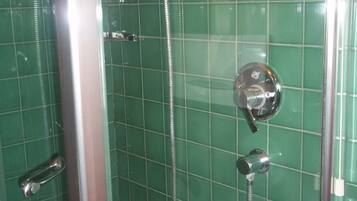 Une cabine de douche dotée d’un pommeau de douche chromé et d’un flexible de douche.