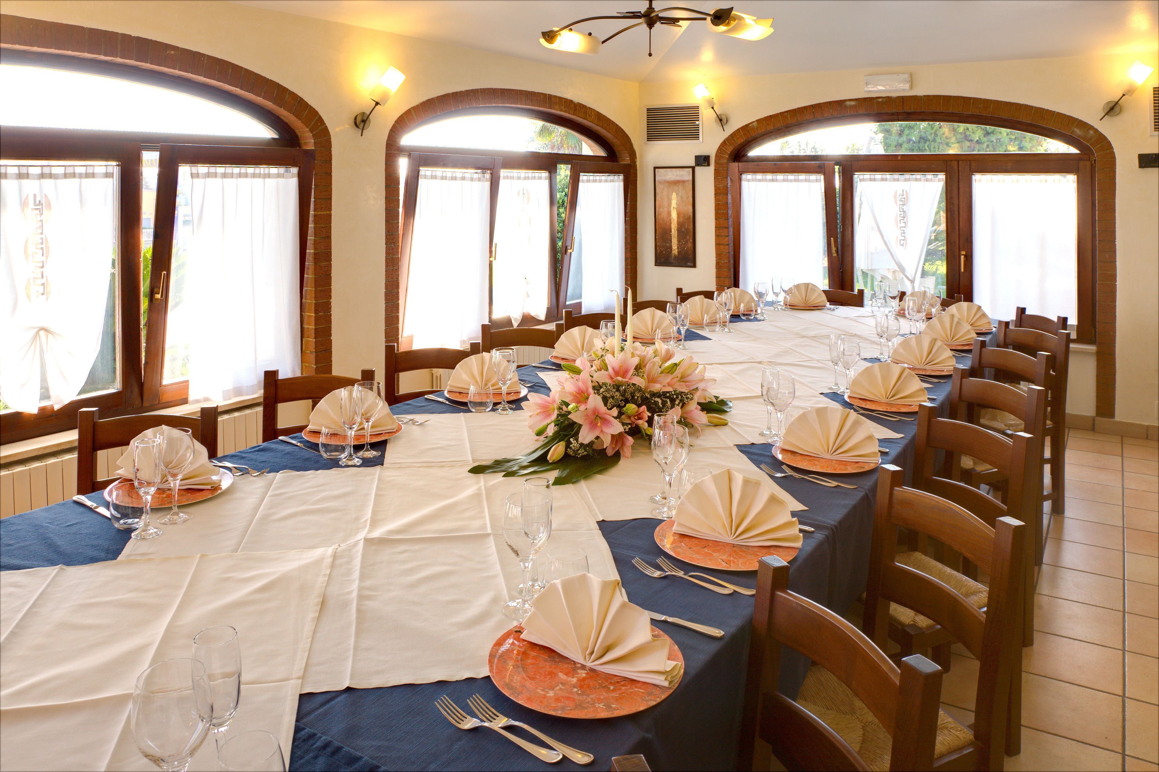 Un coin repas avec une longue table dressée pour le repas, agrémentée d’une nappe bleue, de serviettes blanches et d’un centre de table floral.