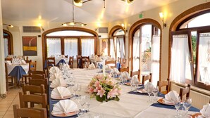 Un comedor con mesas dispuestas para una comida, con un arreglo floral central.
