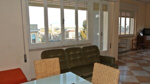 A living room with a sofa, chairs, a table, and a view through large windows. - L'Aura di Sicilia (Ragusa)