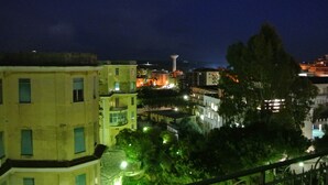 A nighttime view of a cityscape with buildings, a tower, and a lit fountain. - L'Aura di Sicilia (Ragusa)