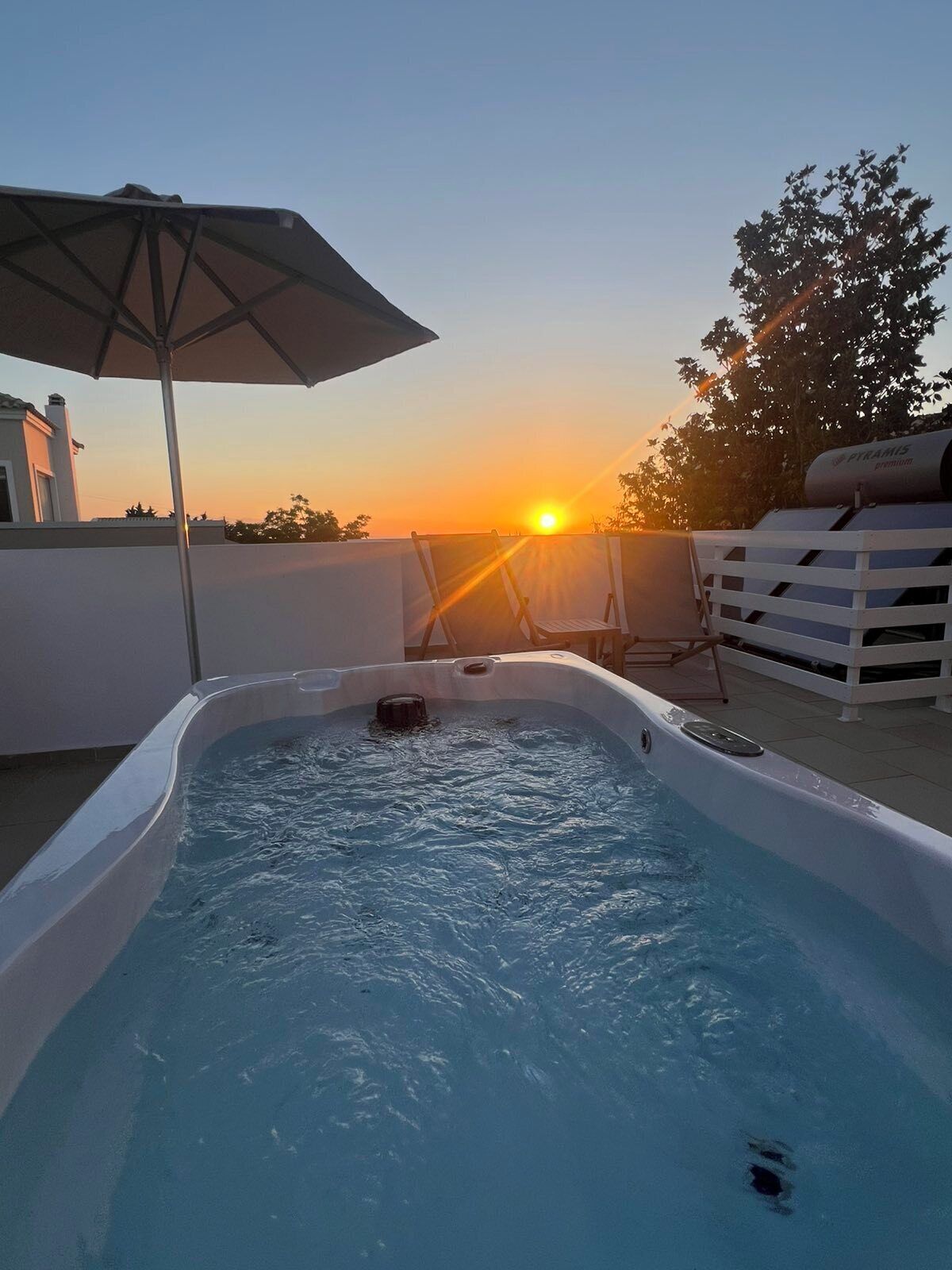 Ein Pool auf dem Dach mit Blick auf den Sonnenuntergang, einer Liege und einem Wasserfiltersystem.