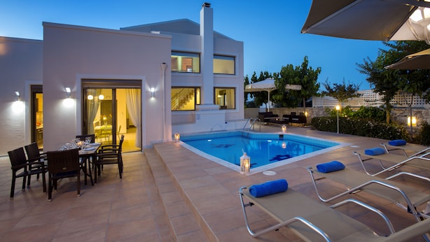 Uma área de piscina moderna ao ar livre com espreguiçadeiras e uma mesa de jantar.