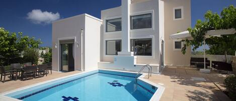 A modern two-story building with a swimming pool in the foreground.