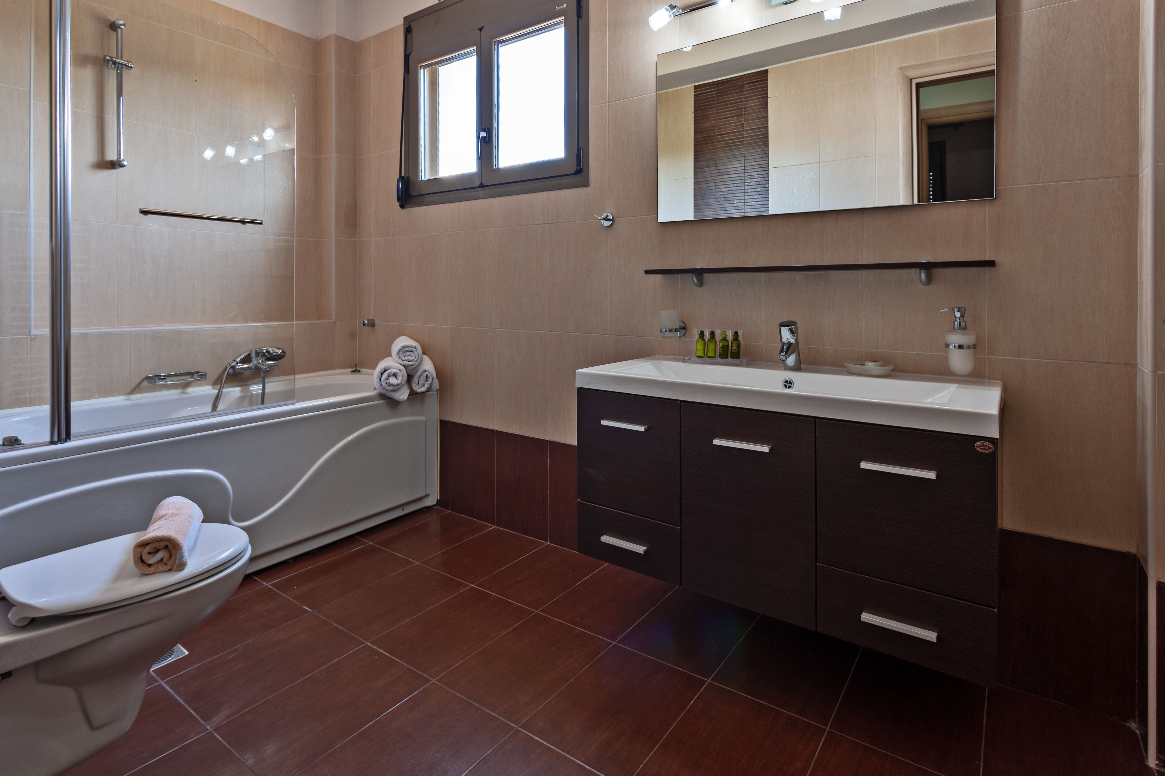 A modern bathroom with a bathtub, toilet, and vanity.