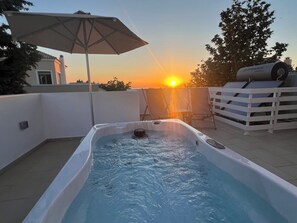 A hot tub with a view of the sunset, a white umbrella, and lounge chairs. - Salvia Villas (Rethymno)
