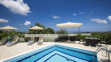 Relax by the pool surrounded by lush greenery and a serene landscape.