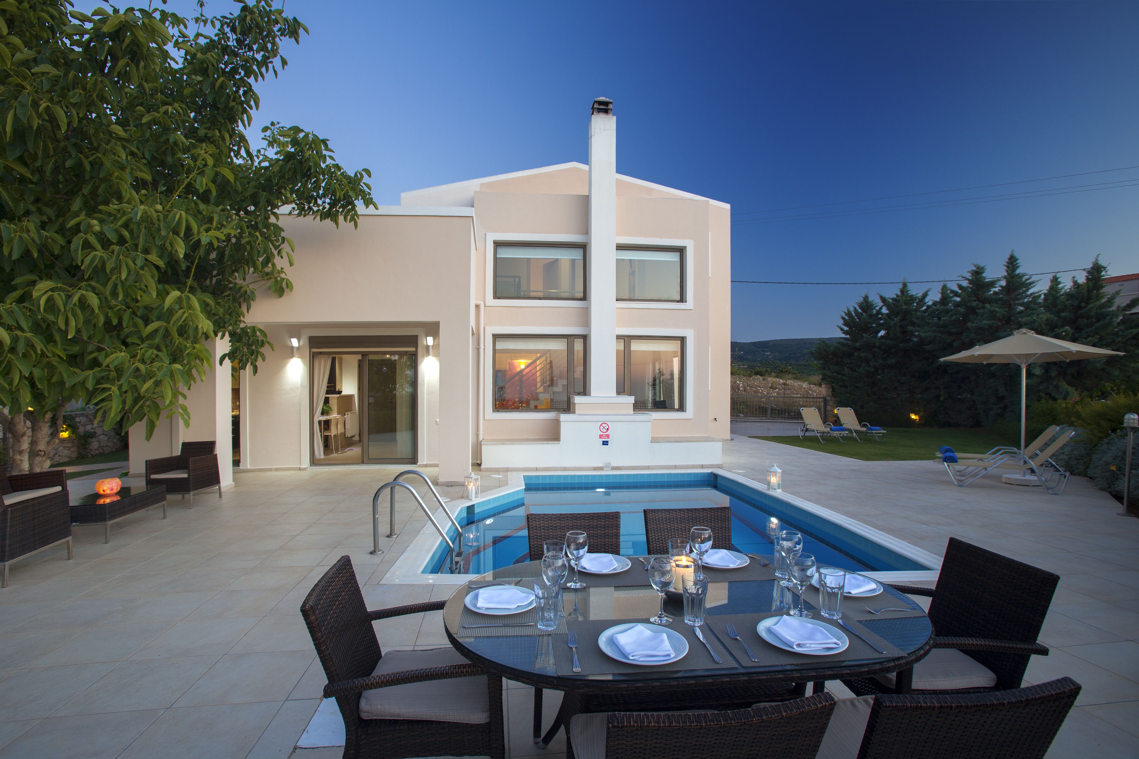 A modern house with a swimming pool, outdoor dining area, and lounge chairs.