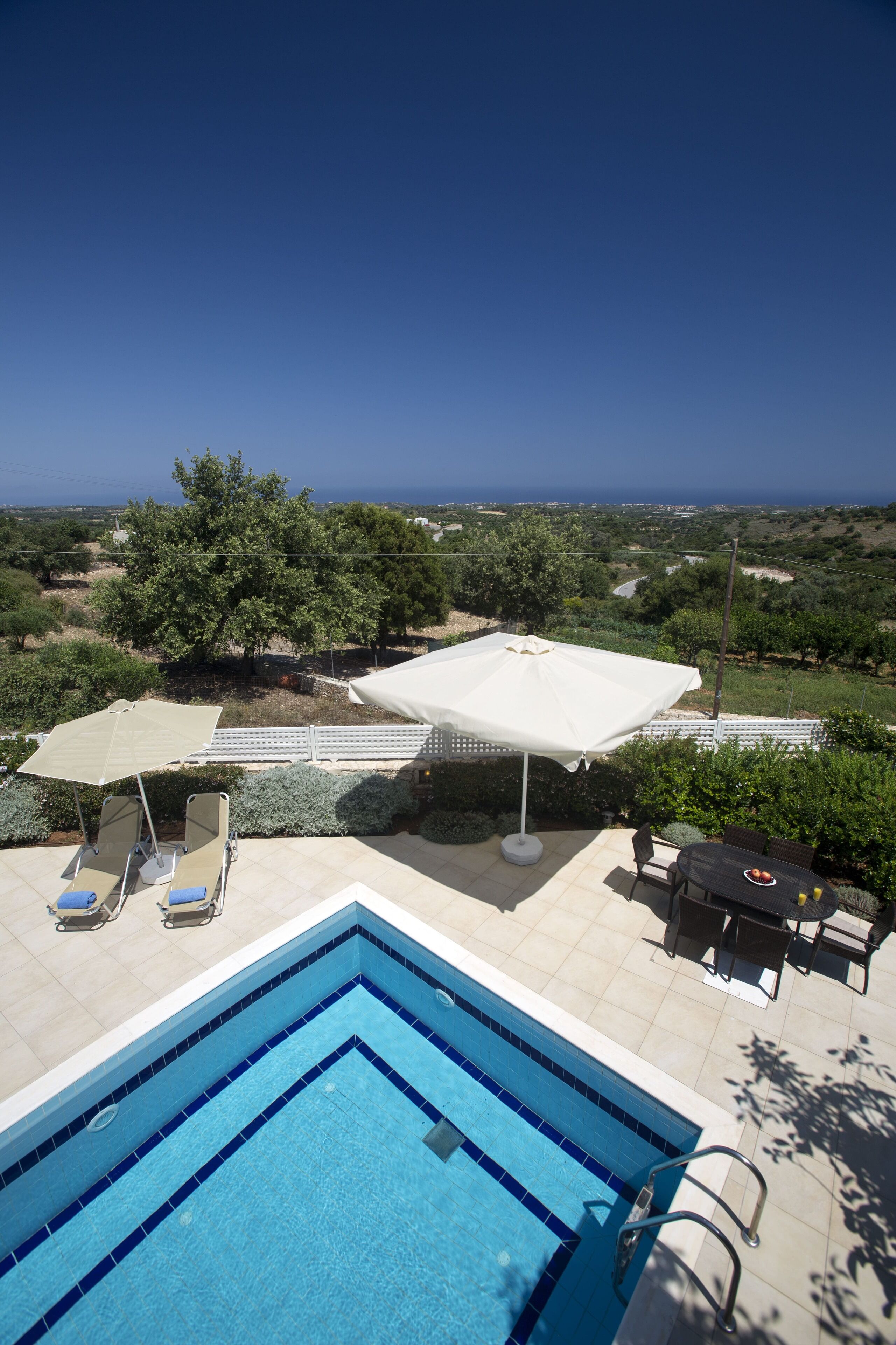 Ein Pool mit Meerblick, eine überdachte Sitzgelegenheit und ein Tisch mit Stühlen.