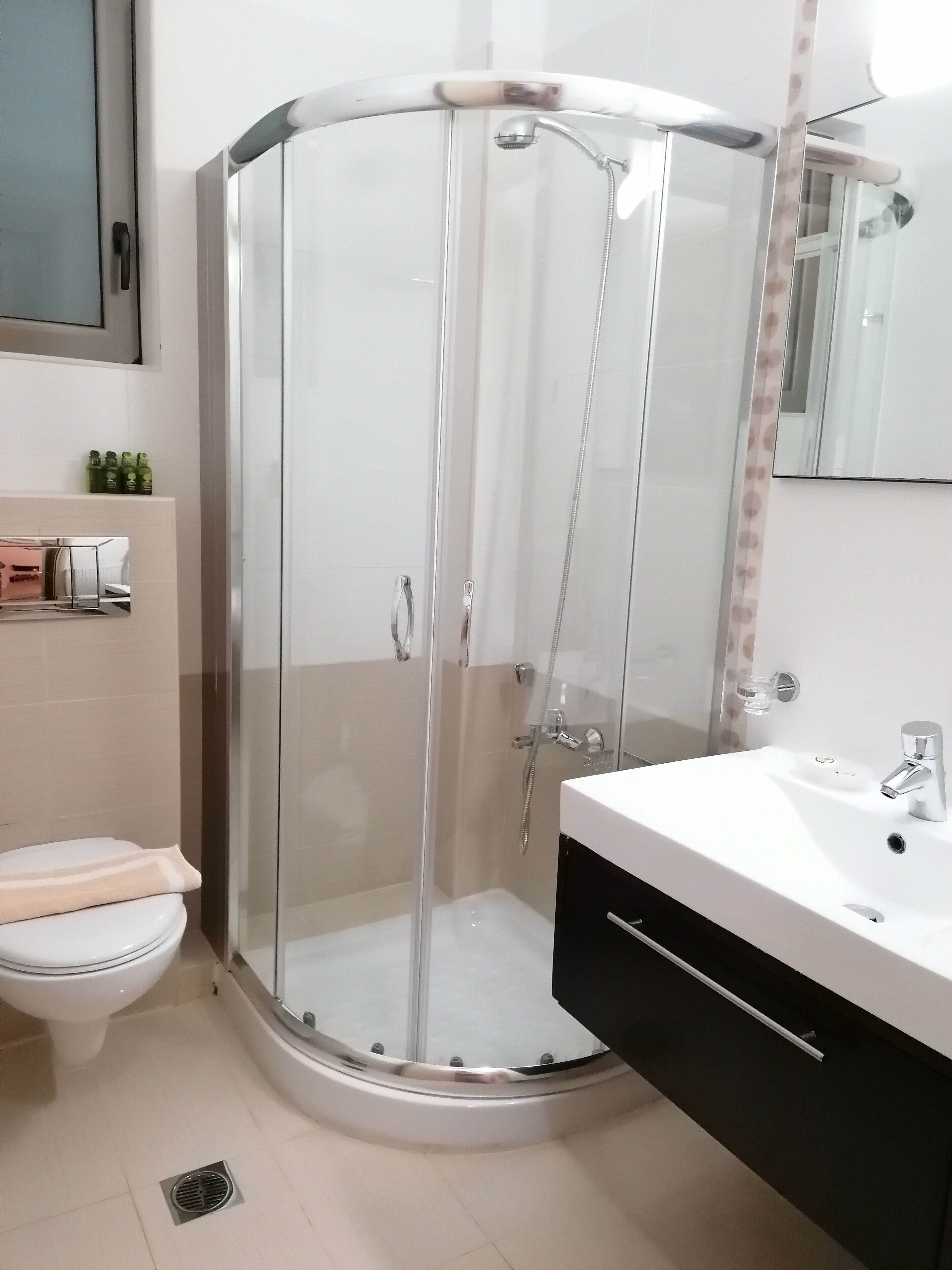 Ein modernes Badezimmer mit einer Duschkabine, einem weißen Waschbecken und einer Toilette.
