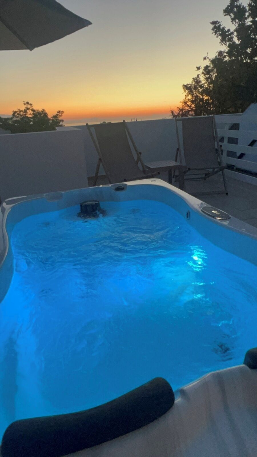 A hot tub with a view of the sunset, surrounded by lounge chairs.