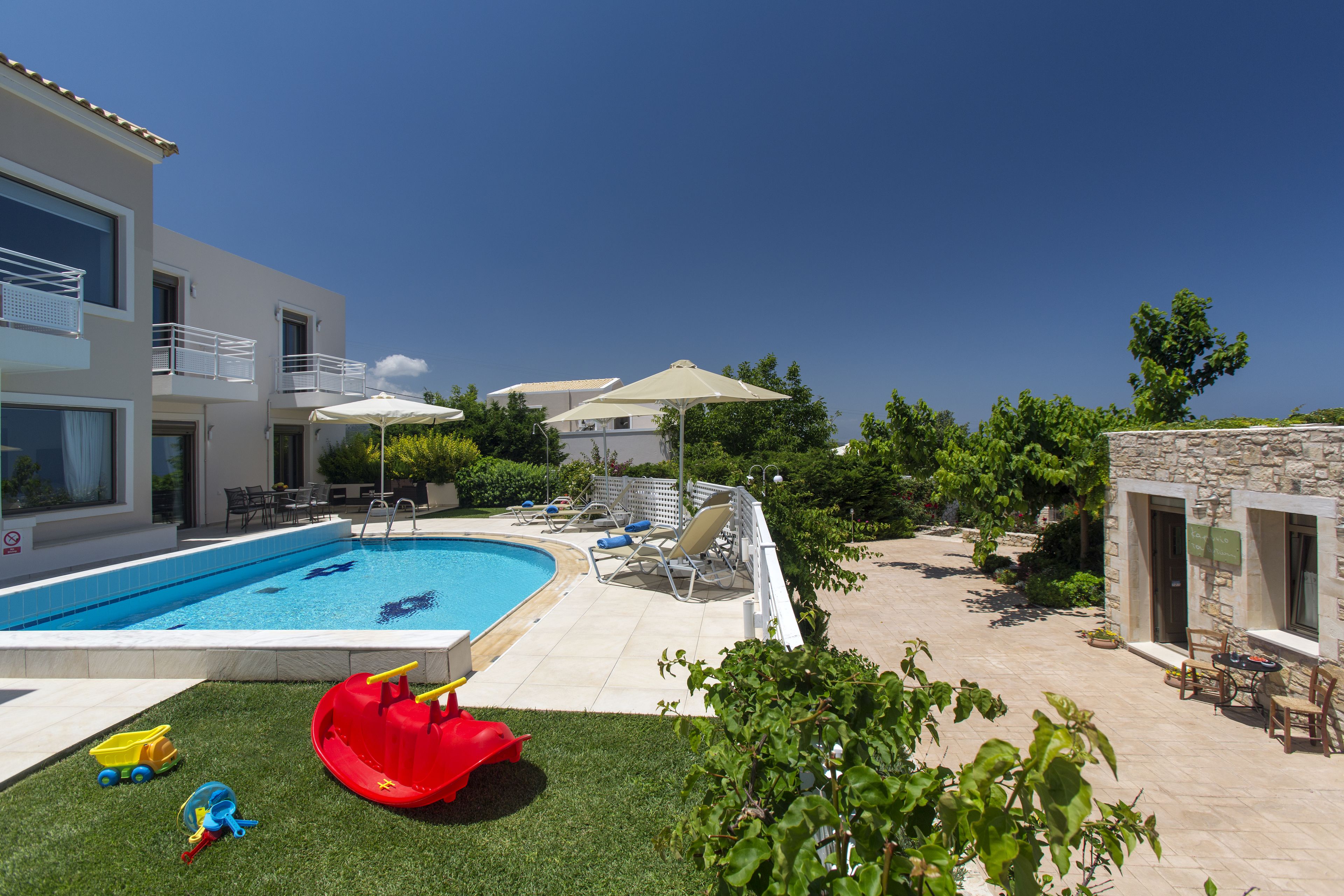 A swimming pool with a slide, lounge chairs, and umbrellas.