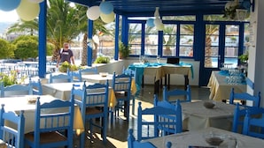An outdoor dining area with blue and white tables and chairs, decorated with balloons. - Hotel Alkyon (Syros)