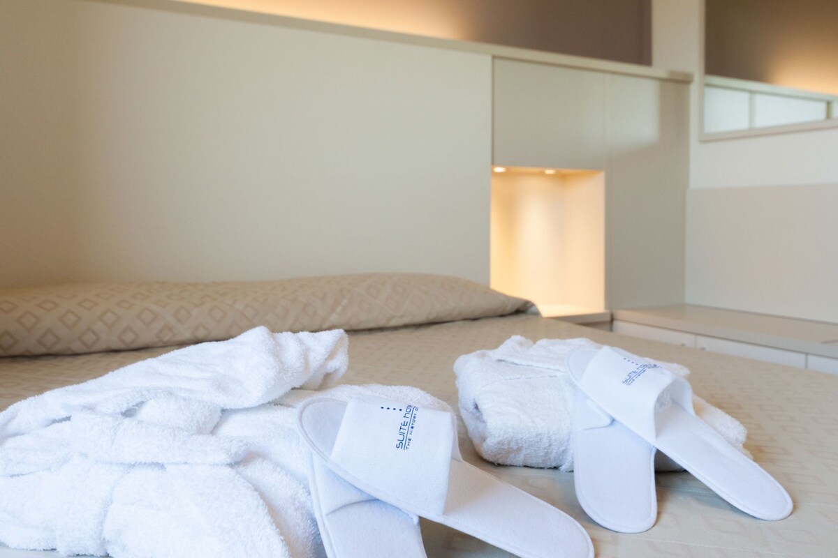 Una habitación de hotel con una cama, una mesita de noche y un espejo.