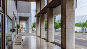 A covered outdoor area with benches, a tiled floor, and a view of the street. - Suite Hotel Elite (Bologna)