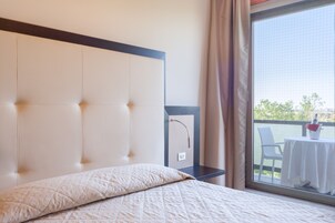 Ett hotellrum med en stor säng, en sänggavel, ett litet bord med en stol och utsikt över omgivningarna.