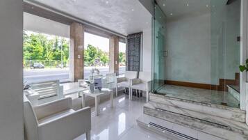 Eine moderne Lobby mit Glastrennung, weißen Möbeln und einer Marmortreppe.