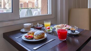 A breakfast table with pastries, a glass of red juice, and a coffee cup. - Suite Hotel Elite (Bologna)