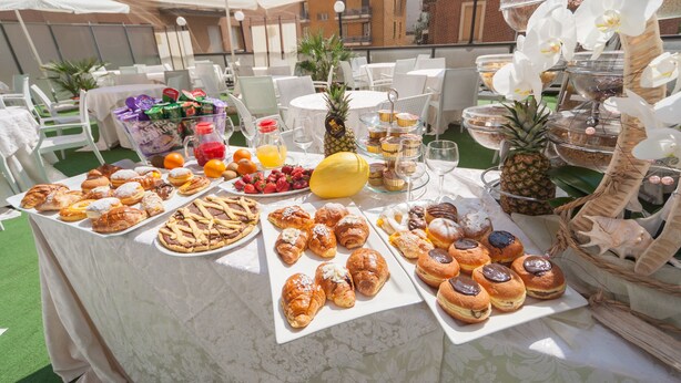 An outdoor buffet with various pastries, fruits, and beverages. - Suite Hotel Elite (Bologna)