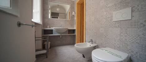 A bathroom with a bidet, toilet, sink, and mirror.