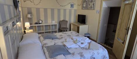 A bedroom with a bed, bedside lamps, a TV, and a wardrobe.