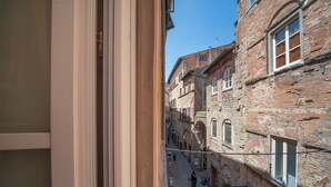 Una calle estrecha con edificios históricos, cielo despejado y gente caminando.