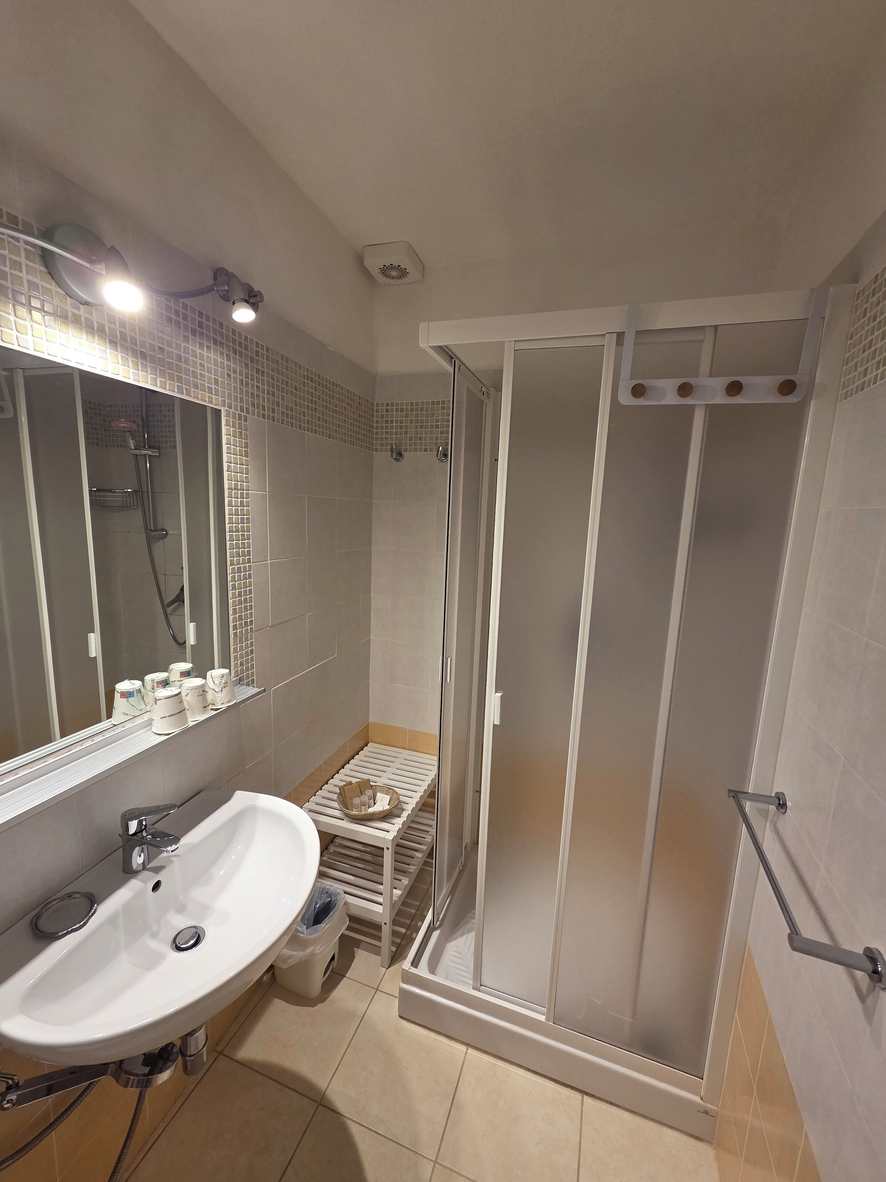 A modern bathroom with a white sink, mirror, and shower area.