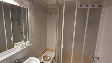 A modern bathroom with a white sink, mirror, and shower area.