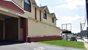 A building with a 'CLEARANCE 10' sign, a garage door, and a parking lot with a 'SLAM' sign. - South Hills Motel (West Mifflin)