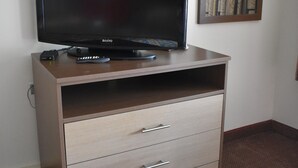 A television on a wooden cabinet with drawers, a remote control, and a power strip. - South Hills Motel (West Mifflin)
