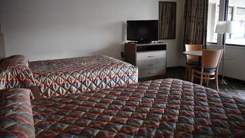 Una habitación de hotel con dos camas, una televisión, un escritorio y una silla.