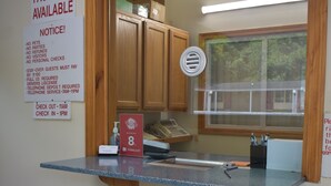 A hotel reception desk with a notice about laundry facilities, a check-in/out schedule, and a red sign for the South Hills Motel. - South Hills Motel (West Mifflin)