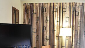 A hotel room with a TV, a small table with two chairs, a lamp, and a window with curtains. - South Hills Motel (West Mifflin)