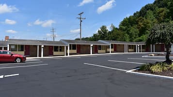 Un motel con varias habitaciones, un estacionamiento y un coche rojo estacionado al frente.