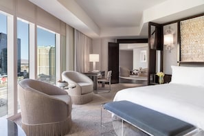 Une chambre d’hôtel moderne, dotée d’un grand lit, de deux fauteuils, d’un bureau et offrant une vue sur le paysage urbain.