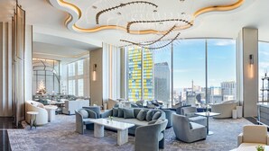 A modern hotel lobby with a large seating area, a chandelier, and a city view. - Waldorf Astoria Las Vegas (Las Vegas)
