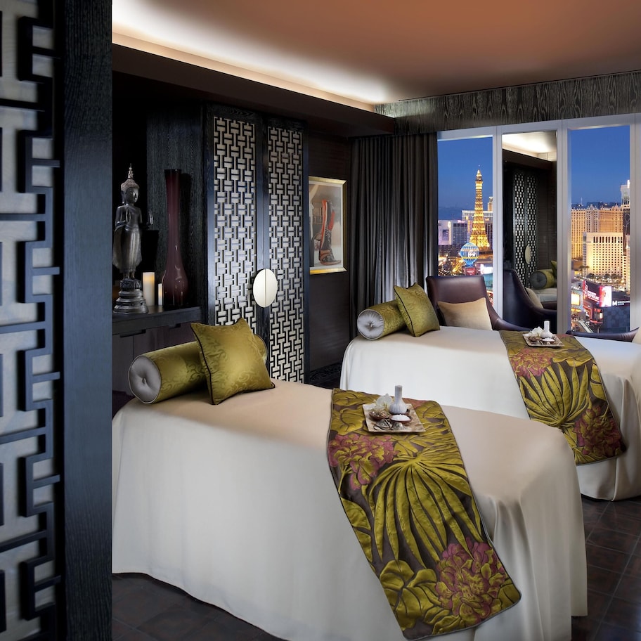 A hotel room with two beds, a view of the cityscape, and a decorative wall panel.