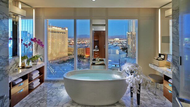 A modern bathroom with a large bathtub, marble flooring, and a city view through floor-to-ceiling windows. - Waldorf Astoria Las Vegas (Las Vegas)
