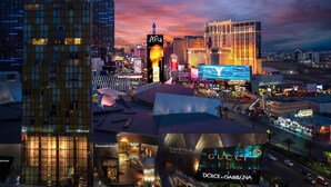 A cityscape with prominent buildings including the Aria, a large hotel with a lit sign, and the Dolce & Gabbana store.
