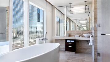Un baño moderno con una bañera grande, un tocador con lavamanos y un espejo amplio.