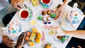 A group of people seated around a table with various food items and tea cups.