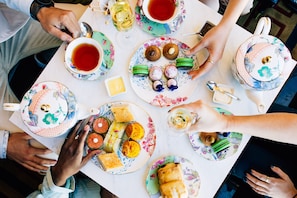 Un groupe de personnes est assis autour d’une table, devant divers plats et des tasses de thé.