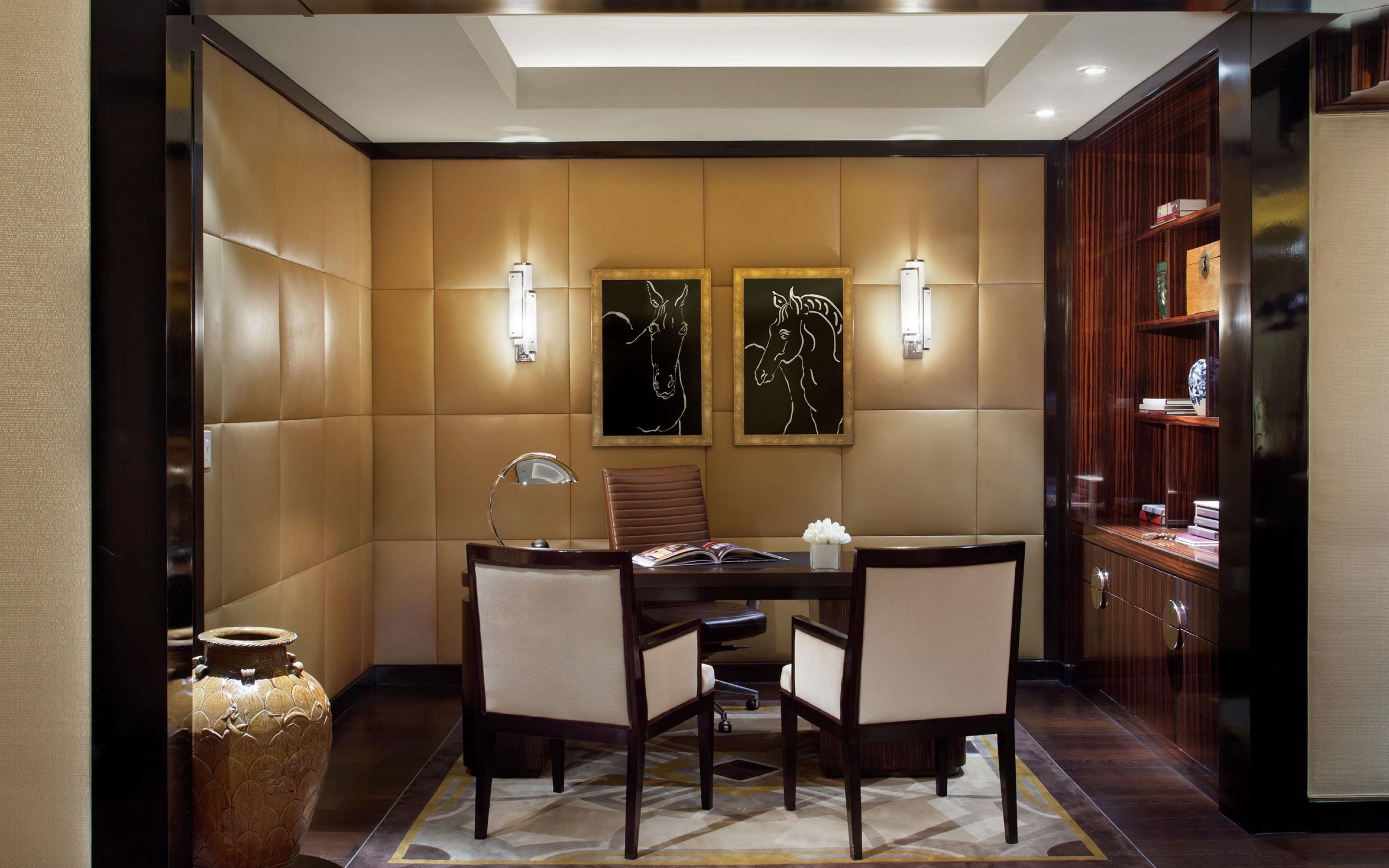 Un salón de conferencias con una mesa, sillas, una lámpara y dos luces fijadas a la pared.