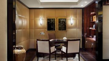 Un salón de conferencias con una mesa, sillas, una lámpara y dos luces fijadas a la pared.