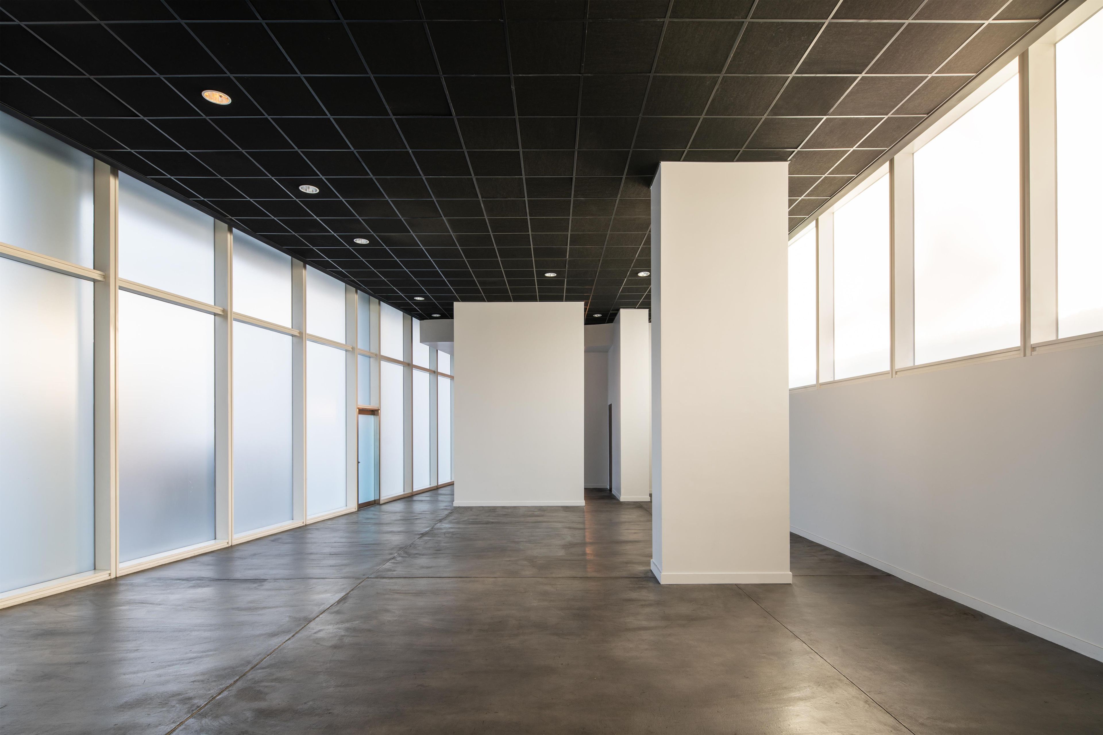 A spacious, modern hallway with a dark ceiling and large windows on one side.