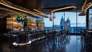 A modern bar with a city skyline view, featuring a bar counter, seating area, and decorative elements. - Waldorf Astoria Las Vegas (Las Vegas)