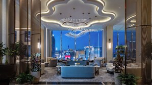 A modern hotel lobby with a large seating area, a decorative ceiling, and a view of the cityscape. - Waldorf Astoria Las Vegas (Las Vegas)